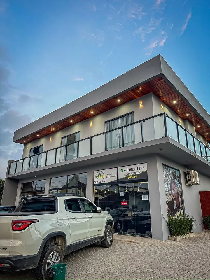 Mesmo prédio comercial depois: fachada pintada em cinza claro com iluminação no beiral