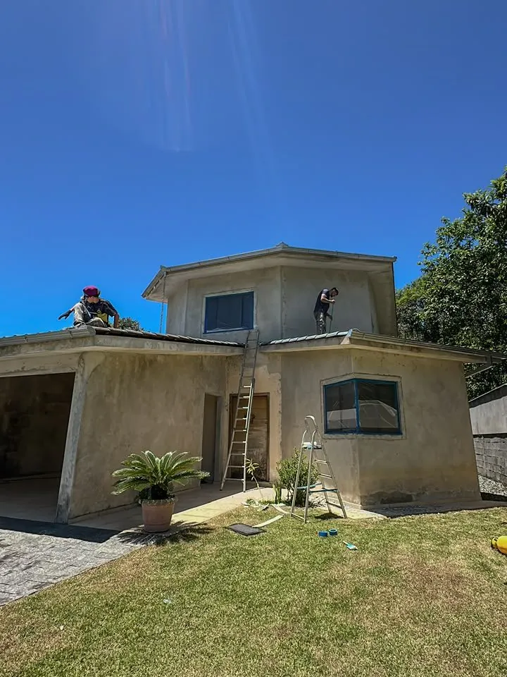 Sobrado com pintura antiga desbotada e equipe da Prime trabalhando no telhado