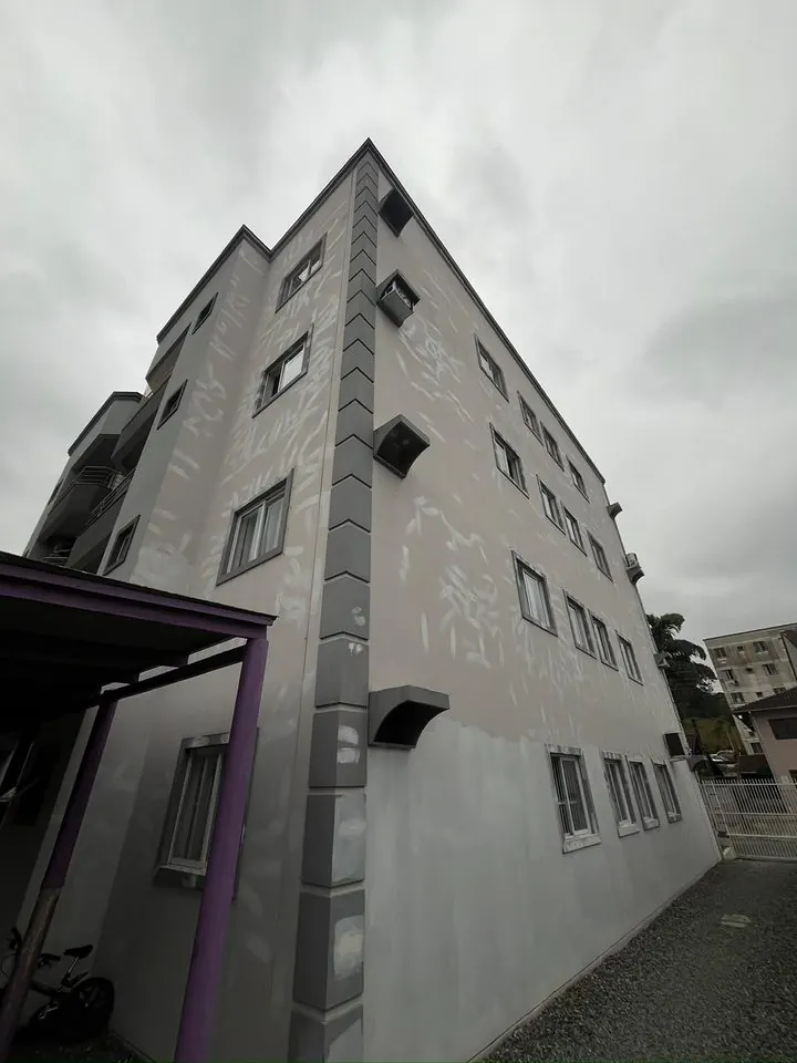 Prédio de quatro andares com a fachada cinza manchada pela chuva
