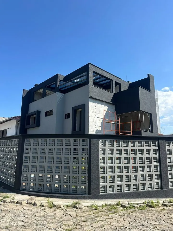 Mesmo sobrado depois: fachada finalizada em preto e branco com revestimento de pedra
