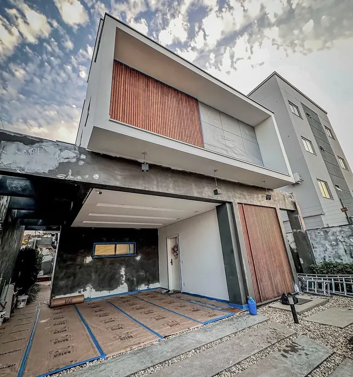 Fachada residencial antes da reforma: reboco cru, sem pintura, obra em andamento