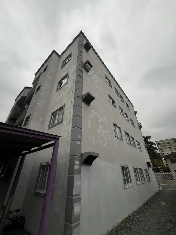 Prédio de quatro andares com a fachada cinza manchada pela chuva