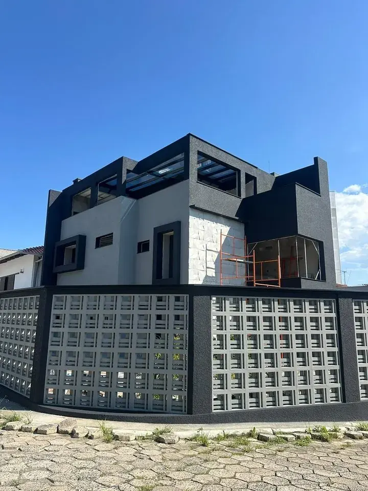 Mesmo sobrado depois: fachada finalizada em preto e branco com revestimento de pedra