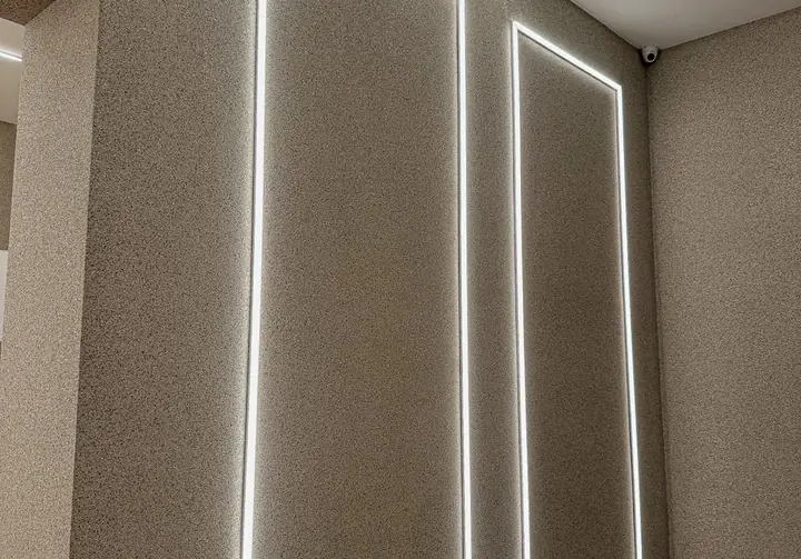 Parede interna revestida com pedras naturais em tom areia, com fita de LED embutida